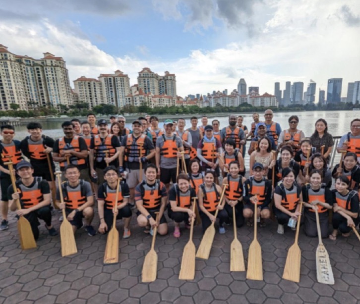 호수 앞에서 구명 조끼를 입은 채로 보트 패들을 들고 있는 직원들